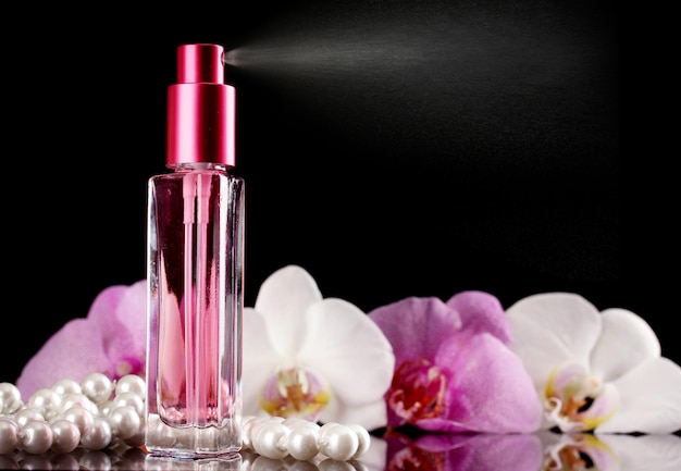 Women's perfume in beautiful bottle and orchid flowers on black background
