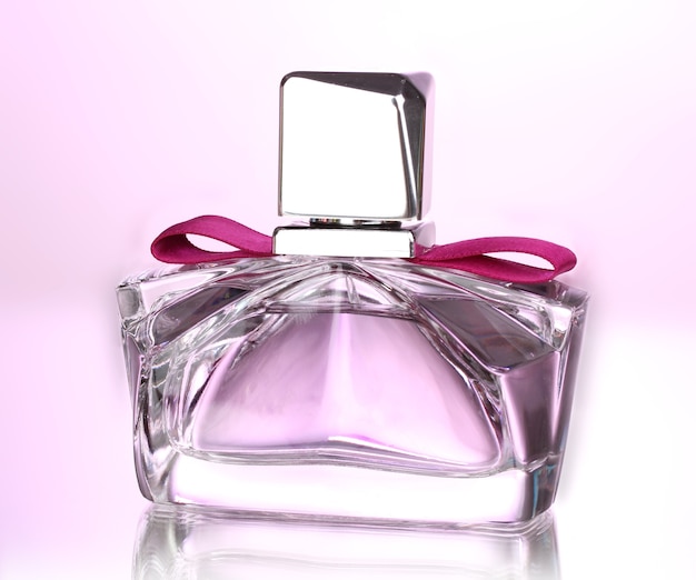 Women's perfume in beautiful bottle on pink surface