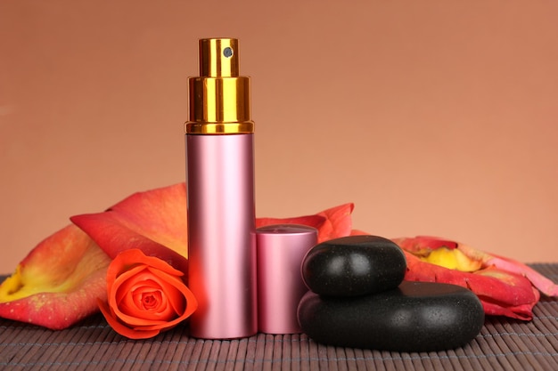 Women's perfume in beautiful bottle with rose on brown background