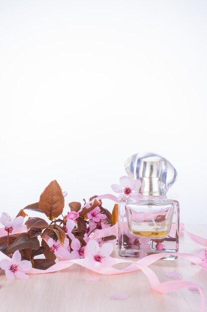 Foto profumo femminile e fiore di ciliegio rosa sakura branch e profumi femminili su sfondo bianco concetto di primavera romantica