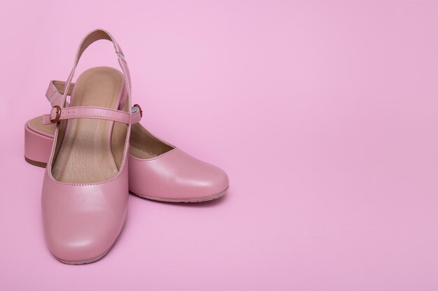 Women's pink summer shoes on a pink background with copy space