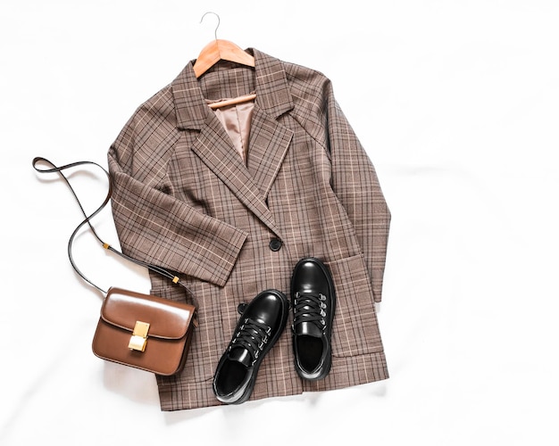 Women's plaid jacket black leather sneakers and cross body bag on a light background top view