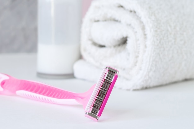 Women's shaving razor with shampoo, towel and antiperspirant on the bathroom 