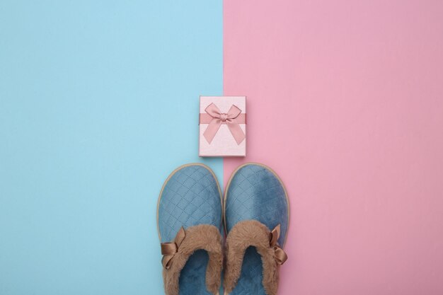 Women's sleeping slippers and gift box on a blue pink pastel background. Christmas concept. Top view