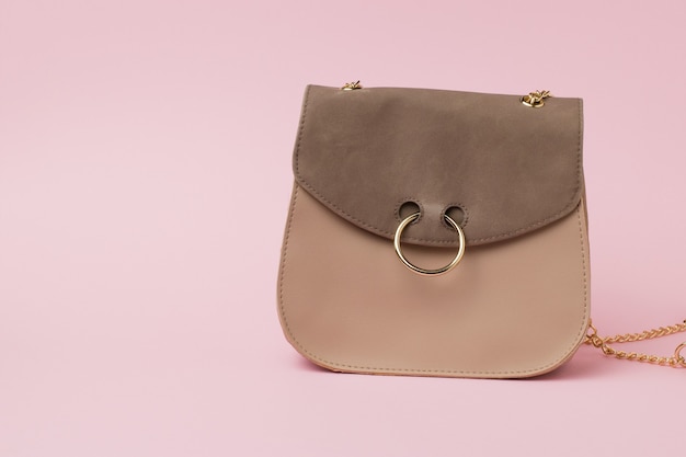 Женская замшевая сумка с золотым кольцом на замке на розовой поверхности