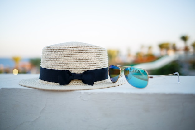 여성용 여름 모자와 안경은 바다가 내려다보이는 테라스에 놓여 있습니다