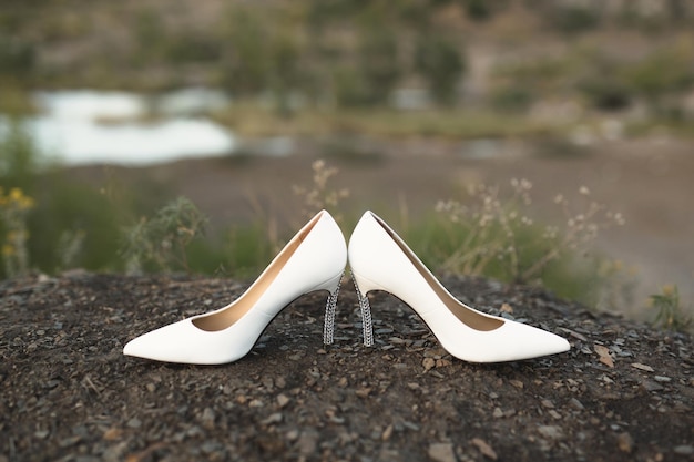 Women's wedding shoes on the ground against the background of the lake