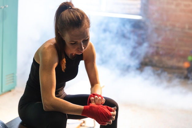 Photo women self defense girl power woman fighter preparing for fight wrapping hands with red boxing wraps
