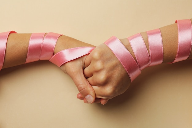 Women shaking hands with pink ribbons