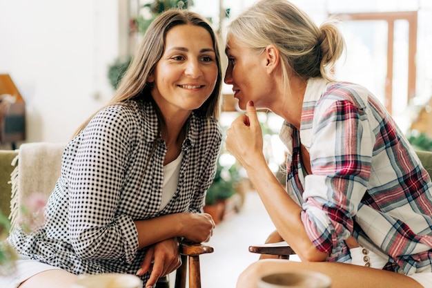 Photo women share gossip and joke talking to each other confidentially in confidential communication