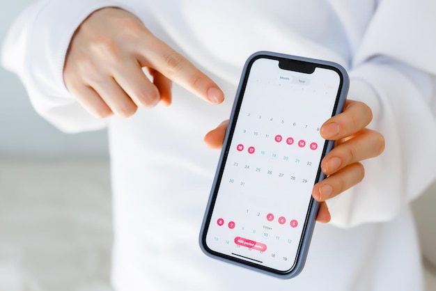 A women showing phone application to track the female cycle ovulation menstruation periods