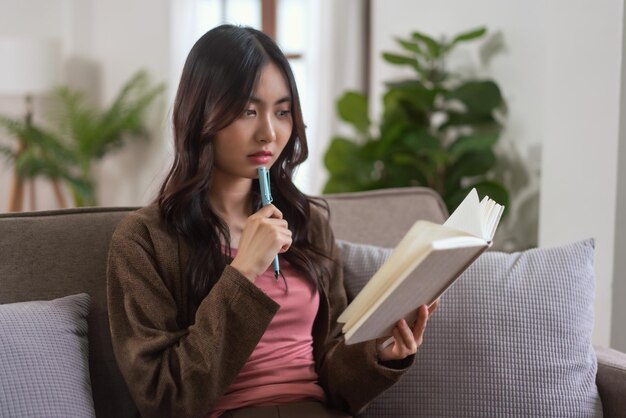 Photo women sit on sofa to thinking and taking notes while reading data on notebook in lifestyle at home