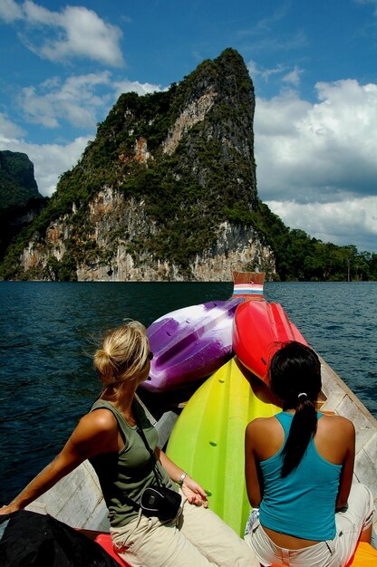 Foto donne sedute su una barca nel lago contro le montagne