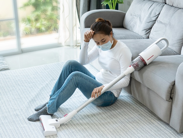 Women sitting on the floor after using  vacuum cleaner cleaning home.