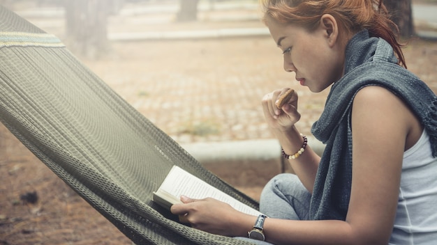 Foto donne sedute a leggere. nell'amaca nell'atmosfera naturale nel parco