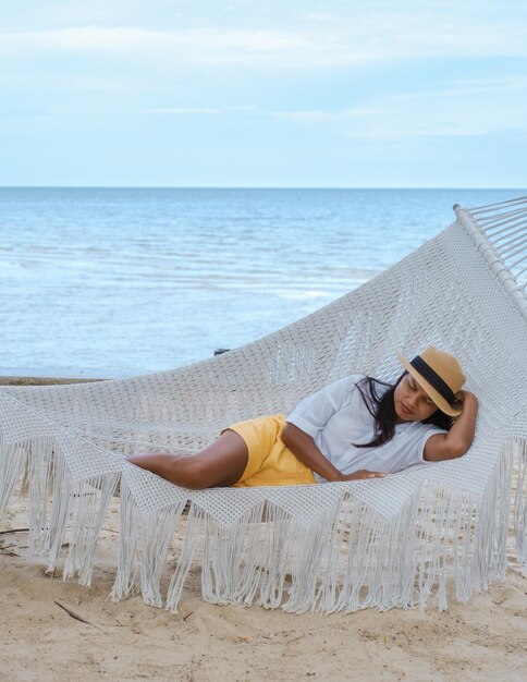 Women sleeping in hammock on a beach in thailand asian women\
taking a nap in afternoon