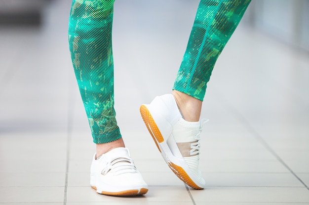 Women slender legs in sports leggings and sneakers in the gym.