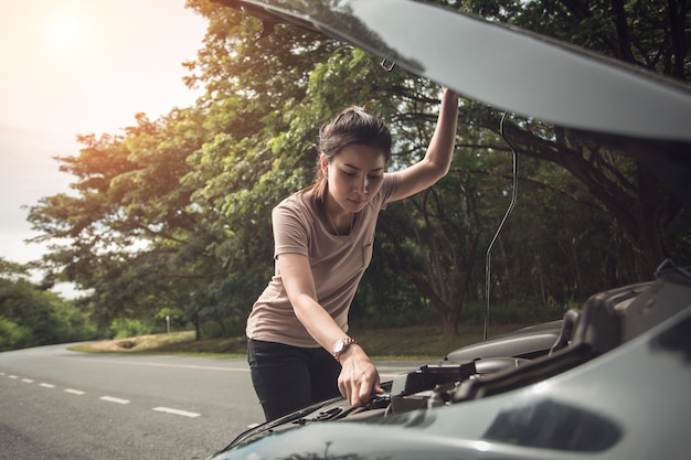 女性の保護彼女はフードを開けた側の壊れた車破損したエンジンを見るか、