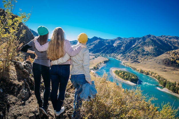 women stand on a hill and look at a mountain river