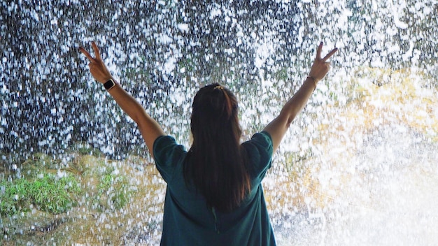 Photo a women standing in front of a waterfall