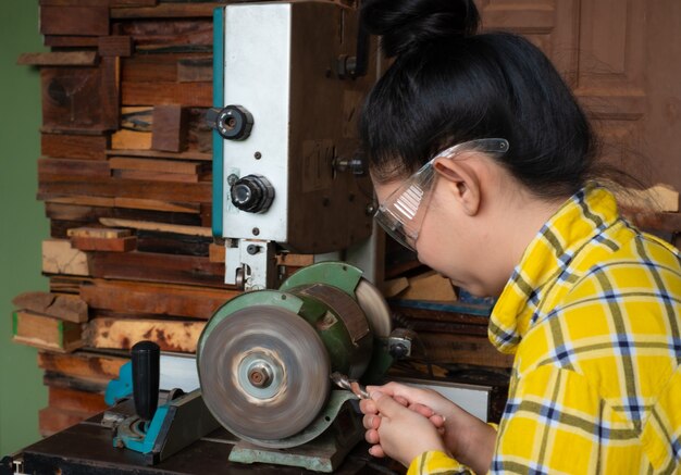 立っている女性は砥石機電動工具で作業台でドリルを研ぐ