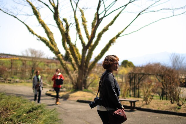 Women standing on road against bare tree