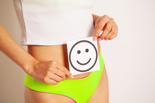 Women stomach health and good digestion concepts, closeup of healthy female with beautiful fit slim body holding white card with happy smile in hands.