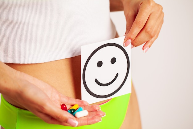 Women stomach health and good digestion concepts, closeup of healthy female with beautiful fit slim body holding white card with happy smile in hands.