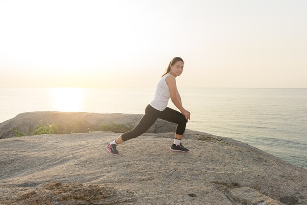 women stretching after sport  with the sea is background and sunrise in morning