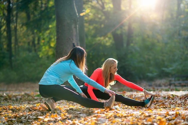 Foto donne che si allungano con un personal fitness trainer dopo l'allenamento nel parco