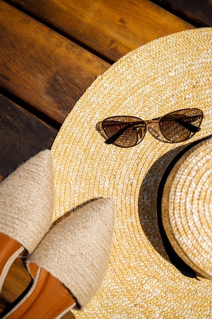 Women summer hat, sunglasses and mules shoes lie on a wooden background. Place for an inscription or advertisement