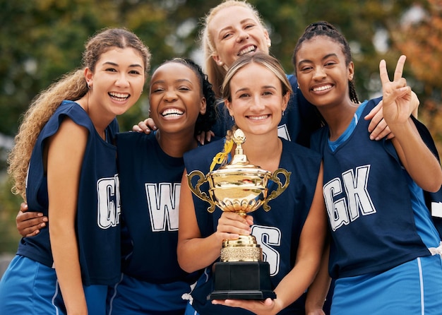 Foto squadra femminile e trofeo vincitore nella partita di allenamento del gioco di fitness o competizione di esercizi sul campo sportivo di netball ritratto sorriso felice o premio sportivo per la diversità del lavoro di squadra o il successo dell'allenamento degli amici