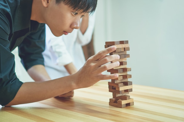 女性とチームワークが空の木製キューブでピラミッドを作る。