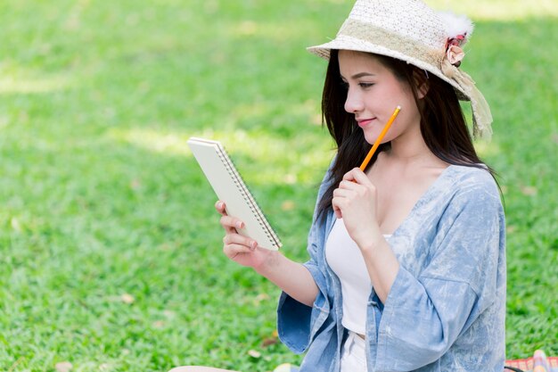 Women thinking to write note script letter in the paper at the garden