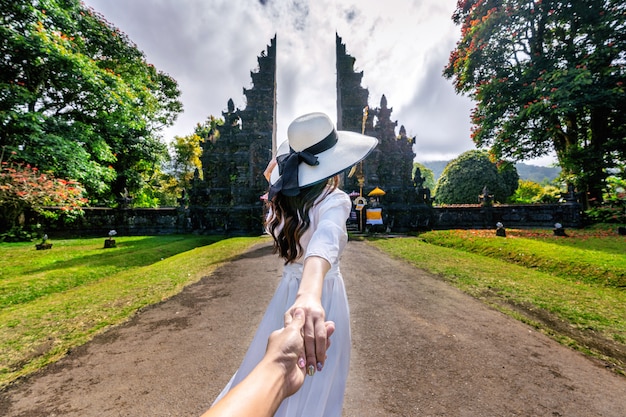 Women tourists holding man's hand and leading him to Big Gate in Bali, Indonesia.