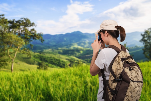 山の夕日で撮影する女性旅行者