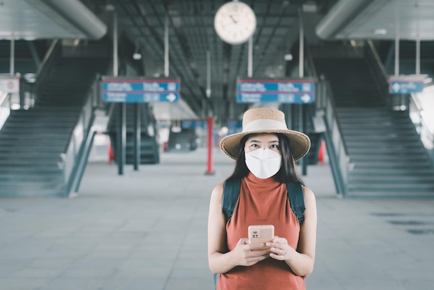 Women traveler using mobile phone during waiting train at train\
stationtravel and vacation concept