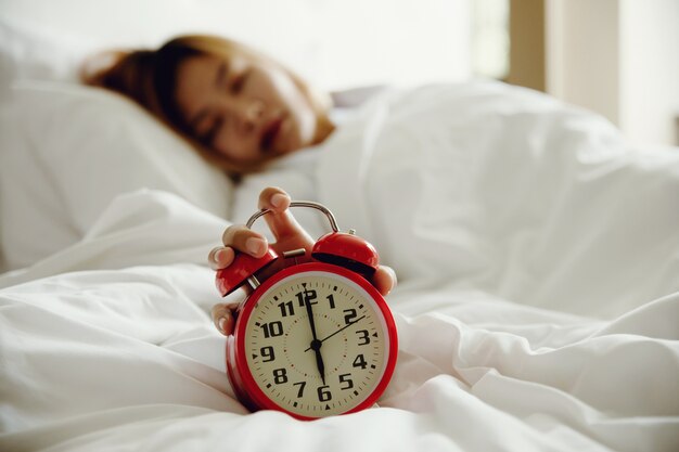 Women turns off the alarm clock waking up in the morning from a call