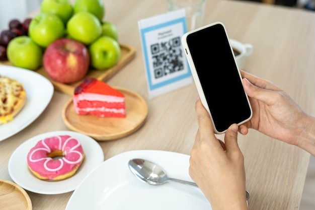 Women use phone to scan qr code to select food menu and collect
points scan to get discounts or pay for food the concept of using a
phone to transfer money or paying money online without cash