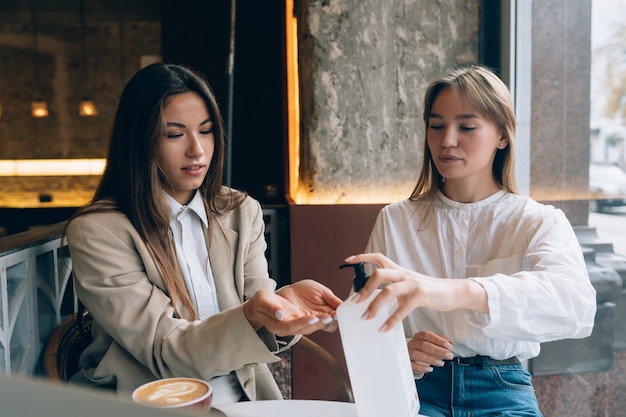 Women using an antibacterial antiseptic to disinfect at cafe