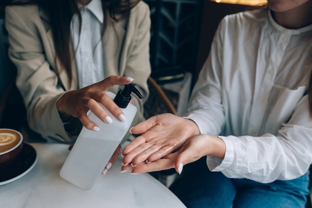 Women using an antibacterial antiseptic to disinfect at cafe