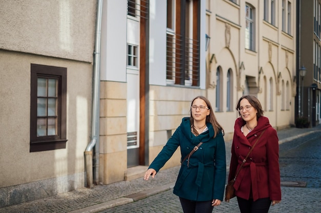 Women walking on footpath against buildings in city
