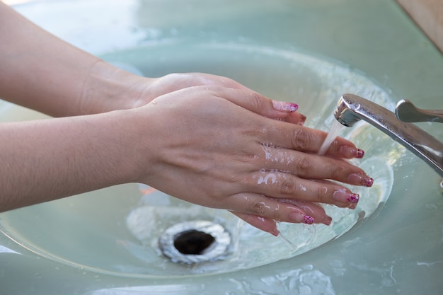 Le donne si lavano bene le mani prima di mangiare con il rubinetto dell'acqua