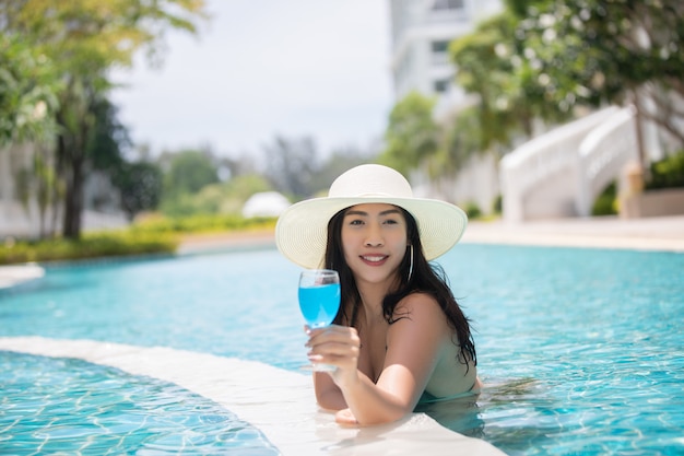 Women wear bikinis and drinking cocktails in the hot summer at the swimming pool.