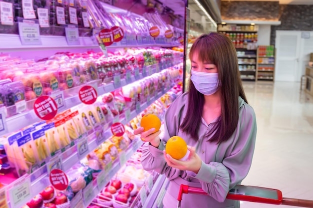 Women wear masks to shop orange fruit in supermarkets, new normal lifestyles in the era of the Corona virus or Covid-19 epidemic