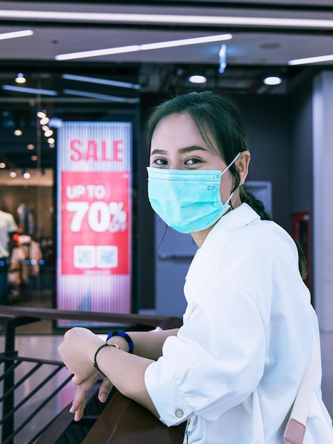 women wearing masks go shopping at the mall stores have put up a discount sign
