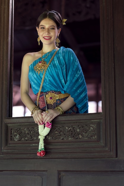 Women wearing Thai national costumes Standing by the window of a Thai house