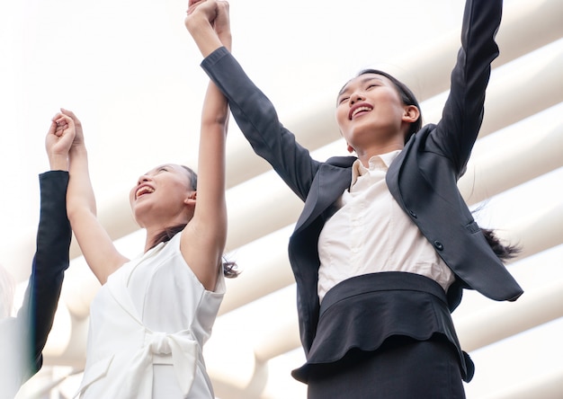 Women wears suit is lifting up hand as successful project