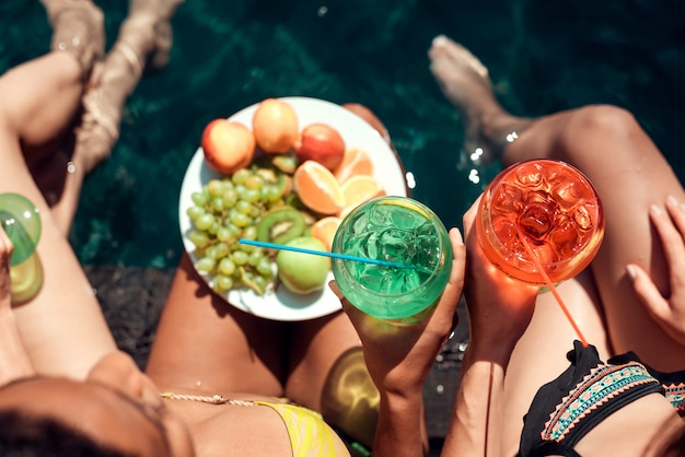 Foto donne con frutta e cocktail a bordo piscina