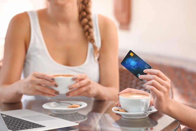 カフェでノートパソコンとクレジットカードを持っている女性